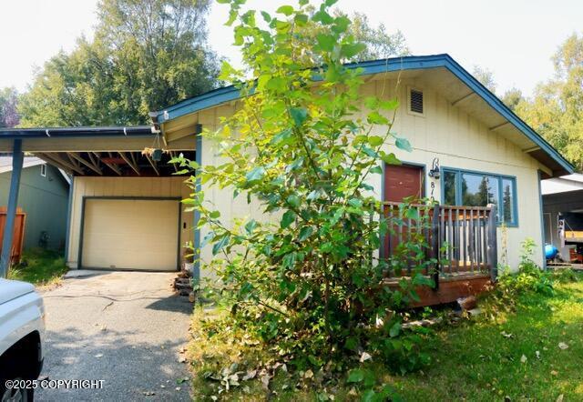 view of front of property featuring a carport, aphalt driveway, a deck, and a garage
