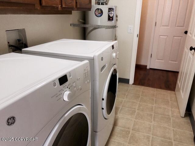 laundry area with baseboards, cabinet space, water heater, and washer and clothes dryer
