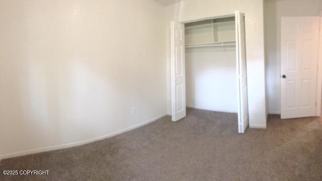 unfurnished bedroom featuring a closet, carpet, and baseboards