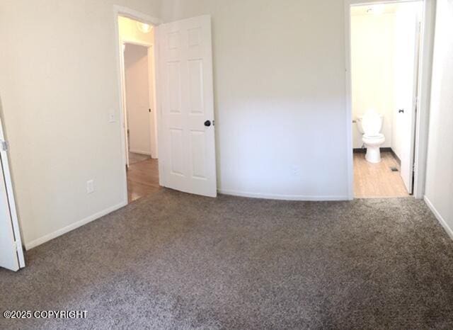 unfurnished bedroom with baseboards, connected bathroom, and carpet flooring