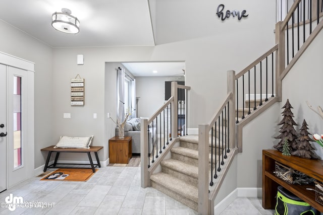 foyer with baseboards and stairway