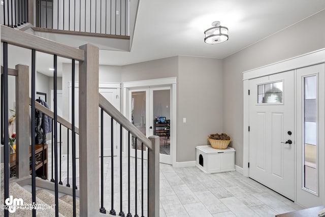 entryway featuring french doors, stairs, and baseboards