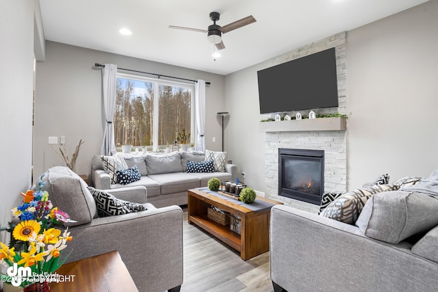 living area with a ceiling fan, recessed lighting, light wood-style flooring, and a fireplace