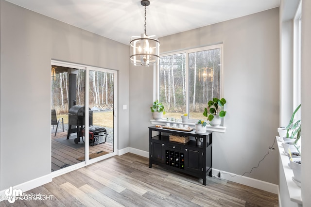 dining space featuring an inviting chandelier, baseboards, and wood finished floors