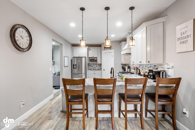 kitchen featuring baseboards, decorative backsplash, a peninsula, and stainless steel appliances