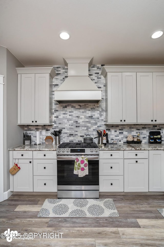 kitchen featuring light stone counters, tasteful backsplash, custom range hood, and stainless steel range with gas cooktop