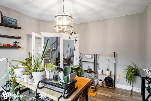 dining area featuring an inviting chandelier, baseboards, wood finished floors, and stairway
