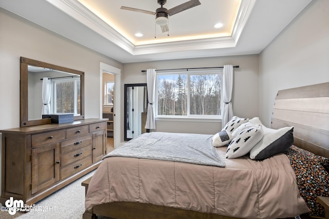 bedroom with ensuite bathroom, a ceiling fan, ornamental molding, a tray ceiling, and carpet flooring