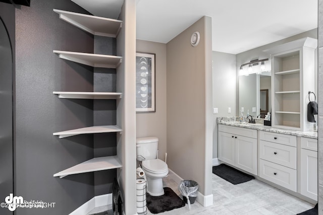 bathroom with vanity, baseboards, and toilet