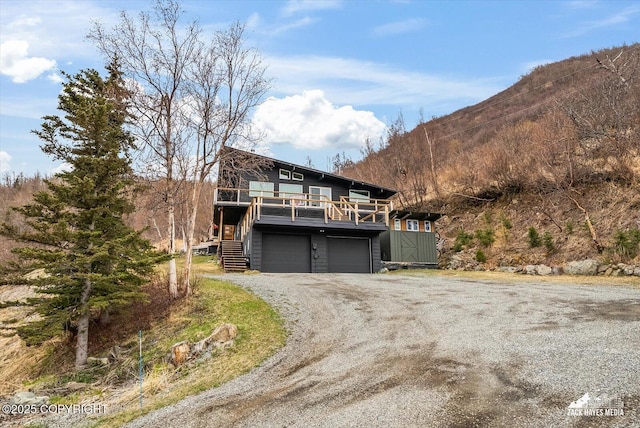 view of front of property with an attached garage, dirt driveway, and a mountain view