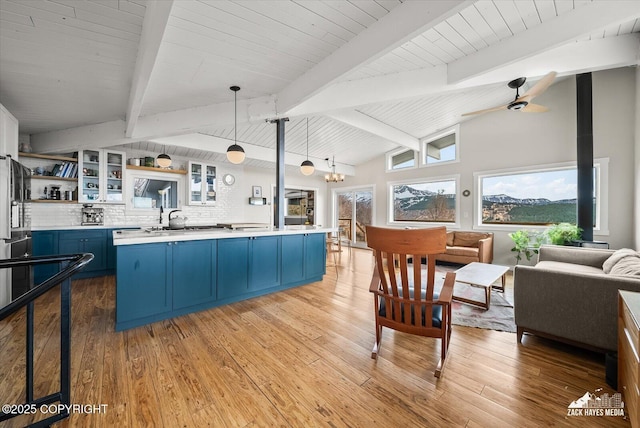 kitchen featuring light countertops, open shelves, lofted ceiling with beams, and blue cabinets