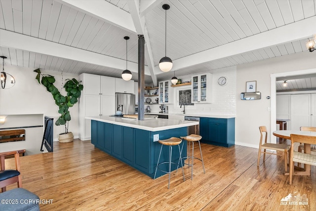 kitchen with a sink, blue cabinetry, appliances with stainless steel finishes, and beam ceiling