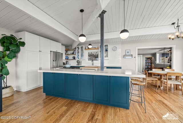kitchen featuring light countertops, stainless steel appliances, blue cabinetry, and open shelves