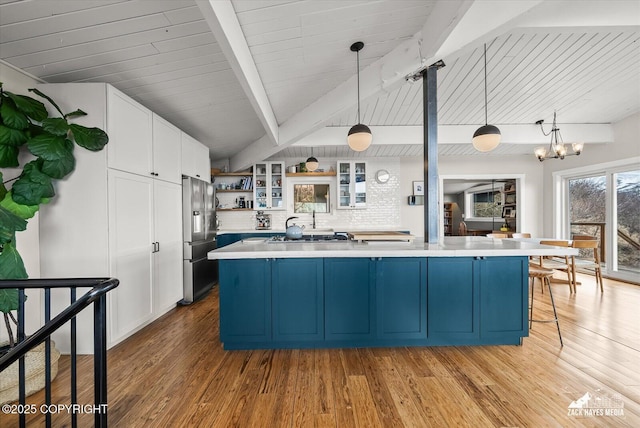 kitchen featuring stainless steel fridge, open shelves, beam ceiling, and light countertops