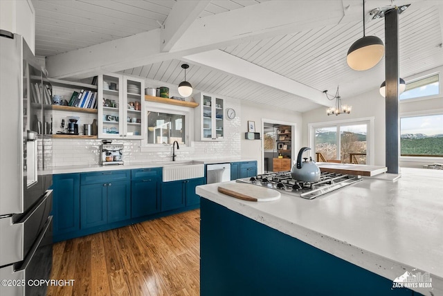 kitchen with stainless steel appliances, blue cabinetry, decorative backsplash, and a sink