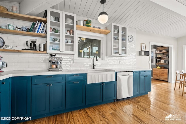 kitchen featuring backsplash, blue cabinetry, open shelves, stainless steel dishwasher, and light countertops