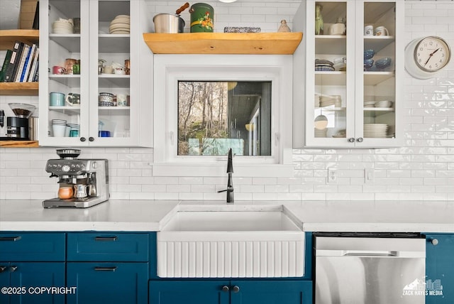interior space with tasteful backsplash, a sink, blue cabinets, and dishwasher