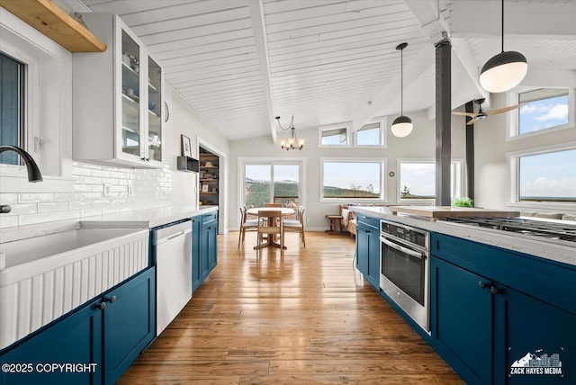 kitchen featuring a sink, stainless steel appliances, vaulted ceiling with beams, tasteful backsplash, and blue cabinets