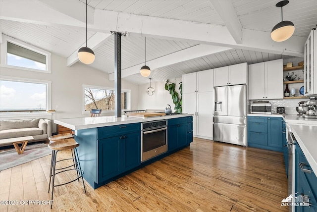 kitchen featuring light countertops, blue cabinetry, appliances with stainless steel finishes, and open shelves