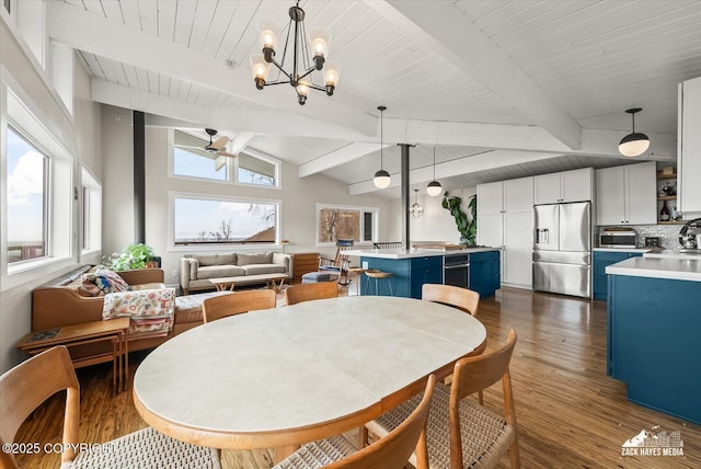 dining room featuring dark wood-style floors, vaulted ceiling with beams, ceiling fan with notable chandelier, and a toaster