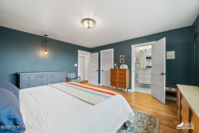 bedroom with baseboards, wood finished floors, and ensuite bath