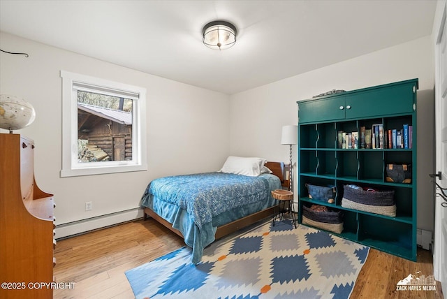 bedroom with wood finished floors and baseboard heating