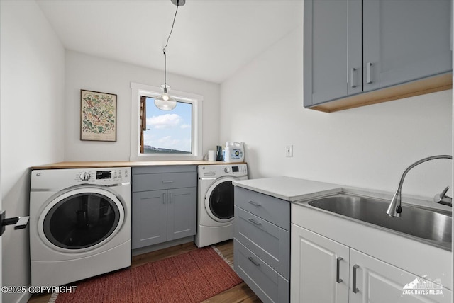 laundry area with separate washer and dryer, a sink, cabinet space, and wood finished floors