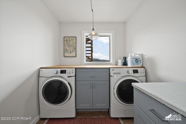 clothes washing area featuring baseboards, dark wood-style flooring, cabinet space, and washer and dryer
