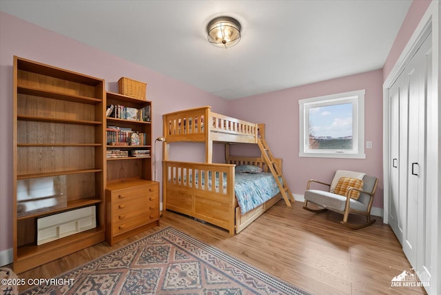 bedroom with baseboards, light wood finished floors, and a closet