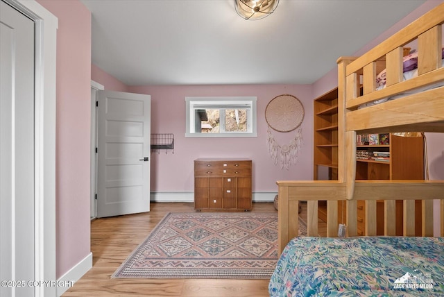 bedroom with baseboards, a baseboard radiator, and wood finished floors