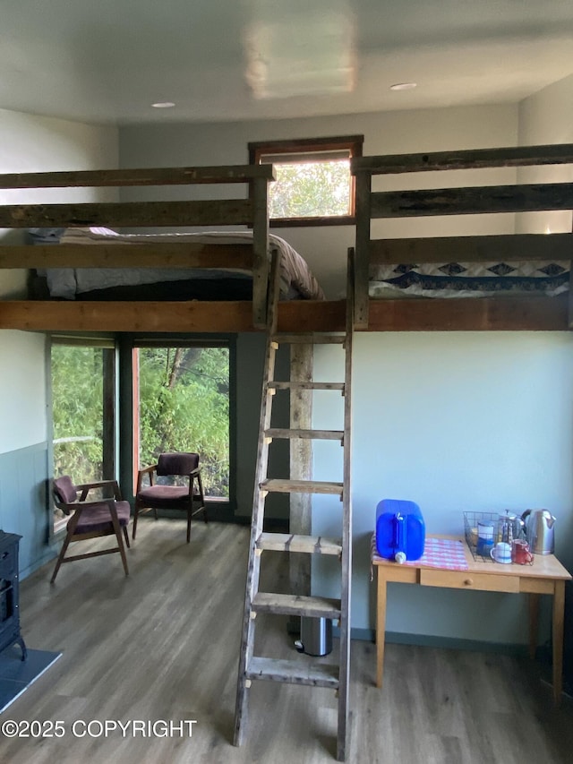 bedroom with a wood stove and wood finished floors