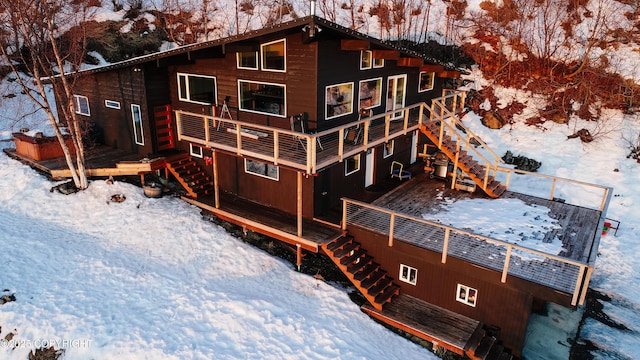 snow covered house featuring a wooden deck and stairway