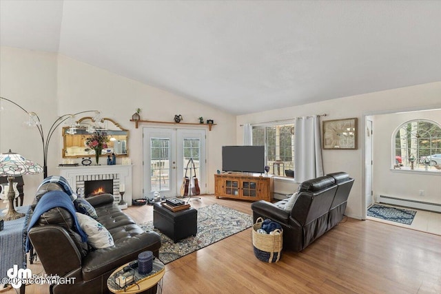 living area featuring vaulted ceiling, a wealth of natural light, wood finished floors, and a baseboard radiator