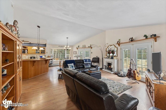 living room with light wood-style flooring, lofted ceiling, a notable chandelier, and a wealth of natural light