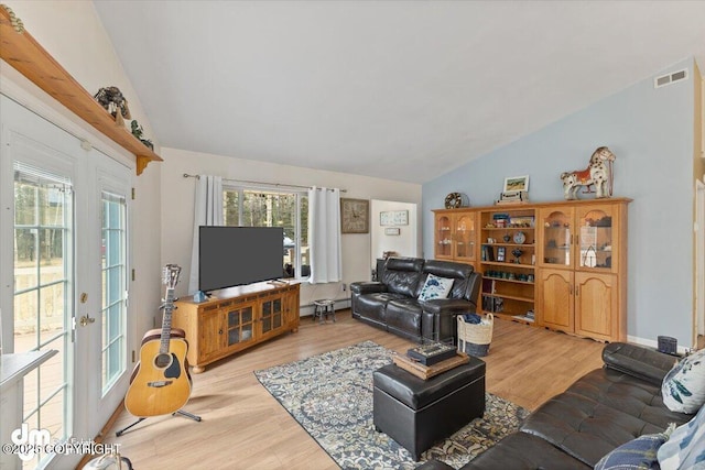 living area with a wealth of natural light, visible vents, light wood-type flooring, and lofted ceiling