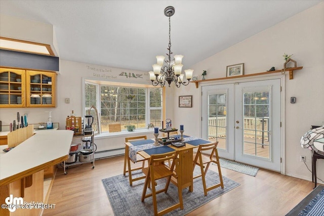 dining room with a notable chandelier, french doors, light wood-style flooring, and lofted ceiling