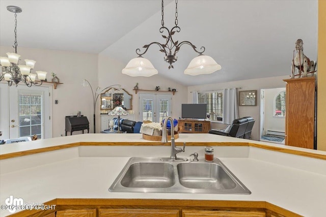 kitchen with an inviting chandelier, open floor plan, light countertops, a sink, and vaulted ceiling