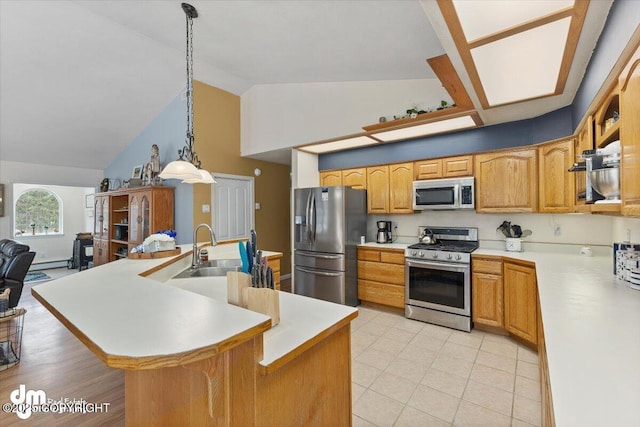 kitchen with appliances with stainless steel finishes, a sink, light countertops, decorative light fixtures, and a center island with sink