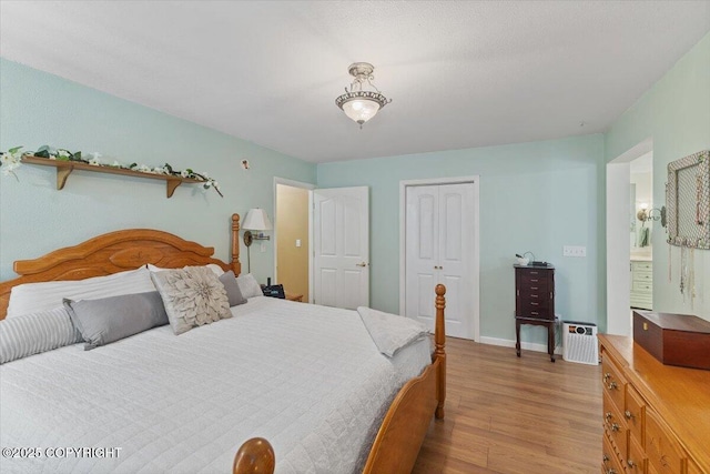 bedroom with baseboards, light wood-style flooring, and a closet