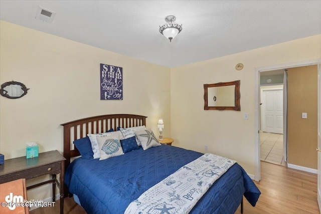 bedroom with visible vents, baseboards, and wood finished floors