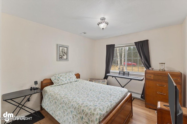 bedroom featuring light wood-style floors and a baseboard heating unit