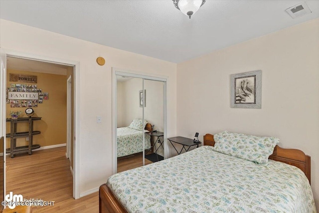 bedroom with a closet, baseboards, visible vents, and light wood-type flooring