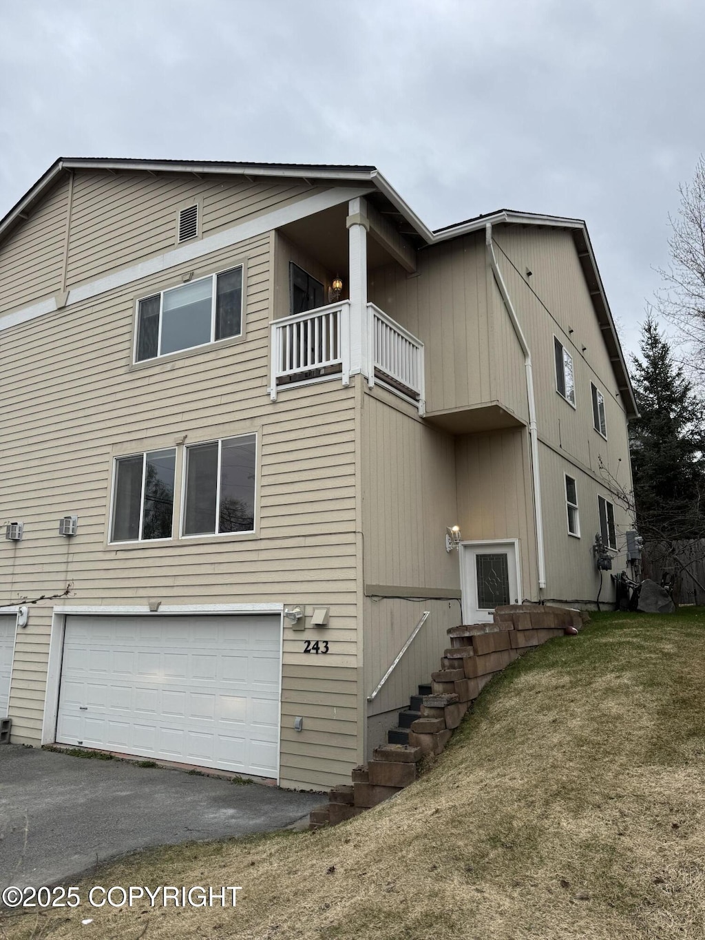 view of property exterior featuring an attached garage, aphalt driveway, and a balcony