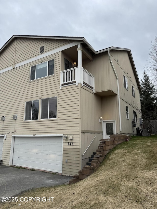 view of property exterior featuring an attached garage, aphalt driveway, and a balcony