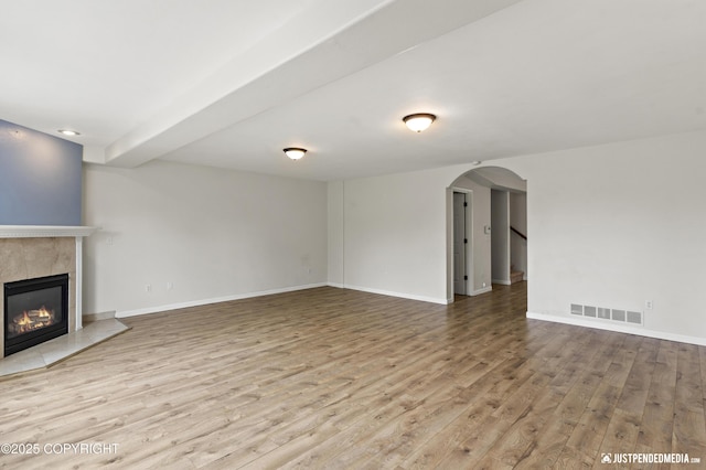 243 Creekside St # 2, Anchorage, AK 99504 - unfurnished living room with wood finished floors, arched walkways, a tile fireplace, and baseboards