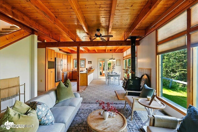 25925 Williamson Ln, Kasilof, AK 99610 - living area featuring a wood stove, healthy amount of natural light, ceiling fan, and a wooden ceiling with exposed beams