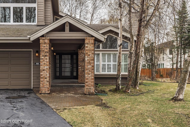property entrance featuring roof with shingles, a garage, fence, aphalt driveway, and a yard