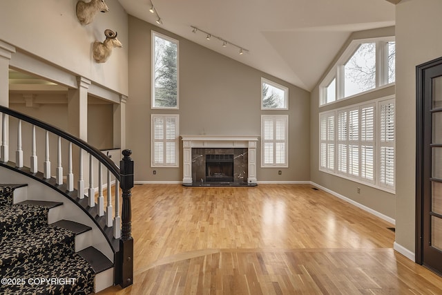 unfurnished living room with rail lighting, wood finished floors, and a wealth of natural light