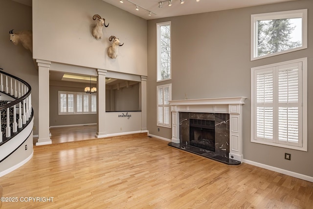 unfurnished living room featuring a towering ceiling, a notable chandelier, stairway, and a high end fireplace
