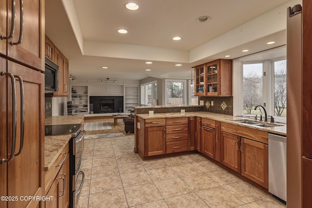 kitchen with a sink, a peninsula, stainless steel appliances, and brown cabinets